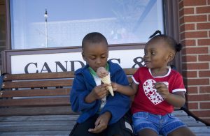 a young girl is sharing her ice cream with a young boy